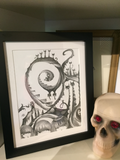 the full picture with a white mat and a simple black frame sitting on a shelf next to a skull with red gems for eyes.
