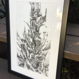 A graphite drawing of a tower sprouting off in many directions, black and white in color, with a white mat and a simple black frame leaned against a wooden staircase behind which plants lurk