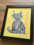 framed cat drawing at a slight angle laying on a wooden table
